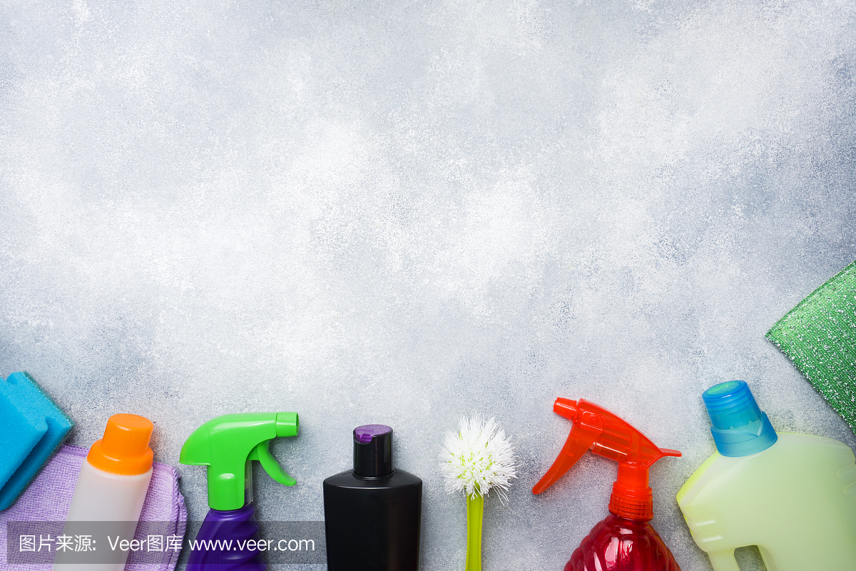 瓶子與洗滌劑,刷子和海綿在混凝土背景。色彩鮮艷的清潔產品。家庭清潔的概念。俯視圖,復制空間。